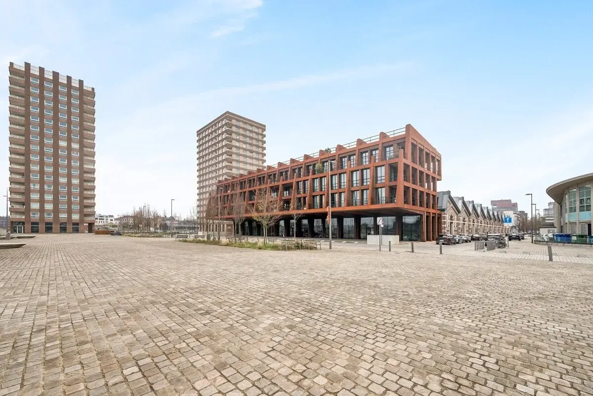 Edificio moderno con facciata in acciaio color ruggine su una piazza lastricata