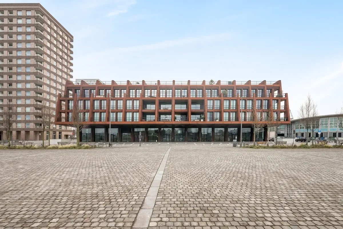 Edificio moderno con facciata in acciaio color ruggine su una piazza lastricata
